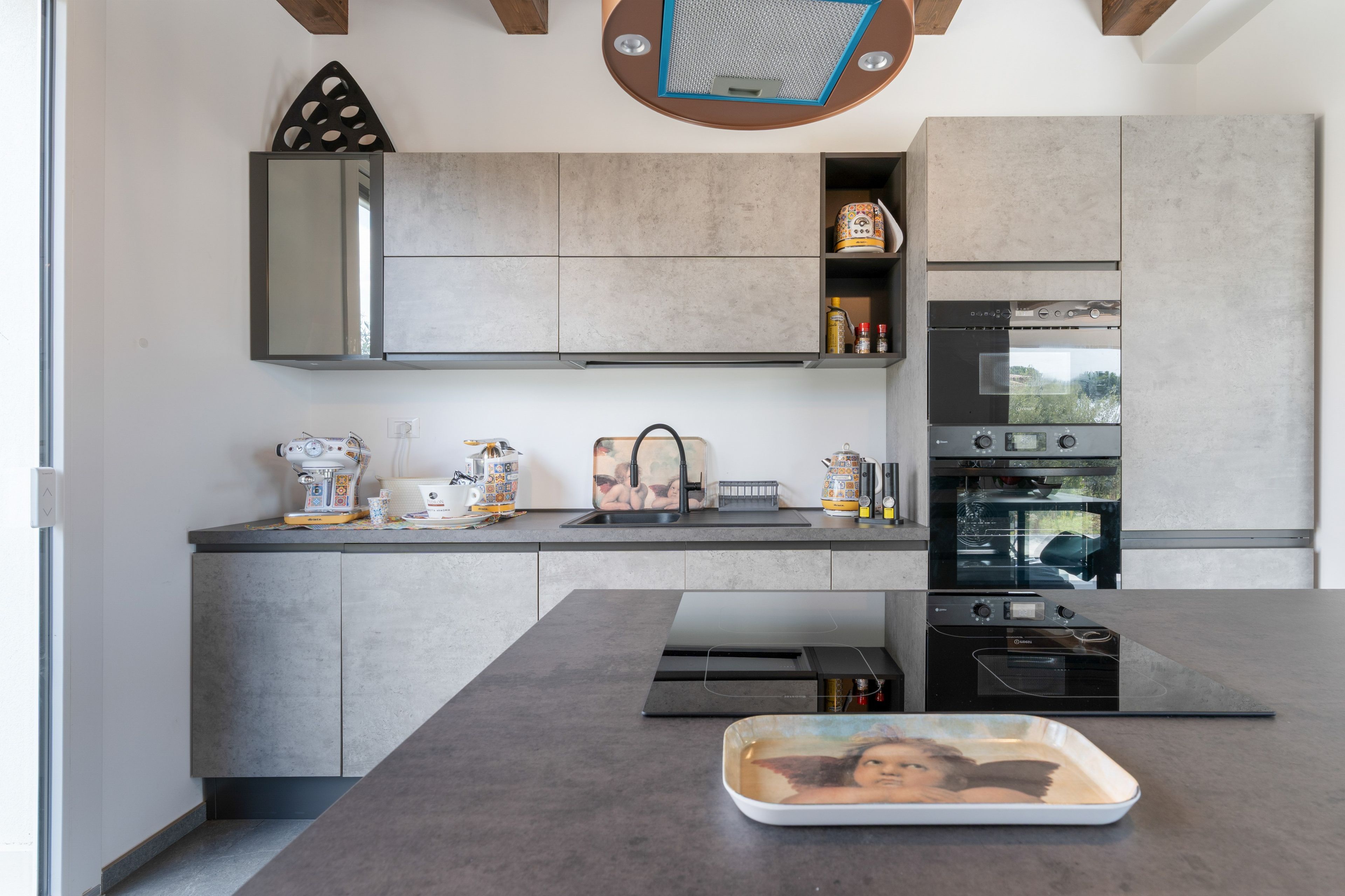 A modern kitchen with a built-in oven, a coffee machine, and a tray with a picture.
