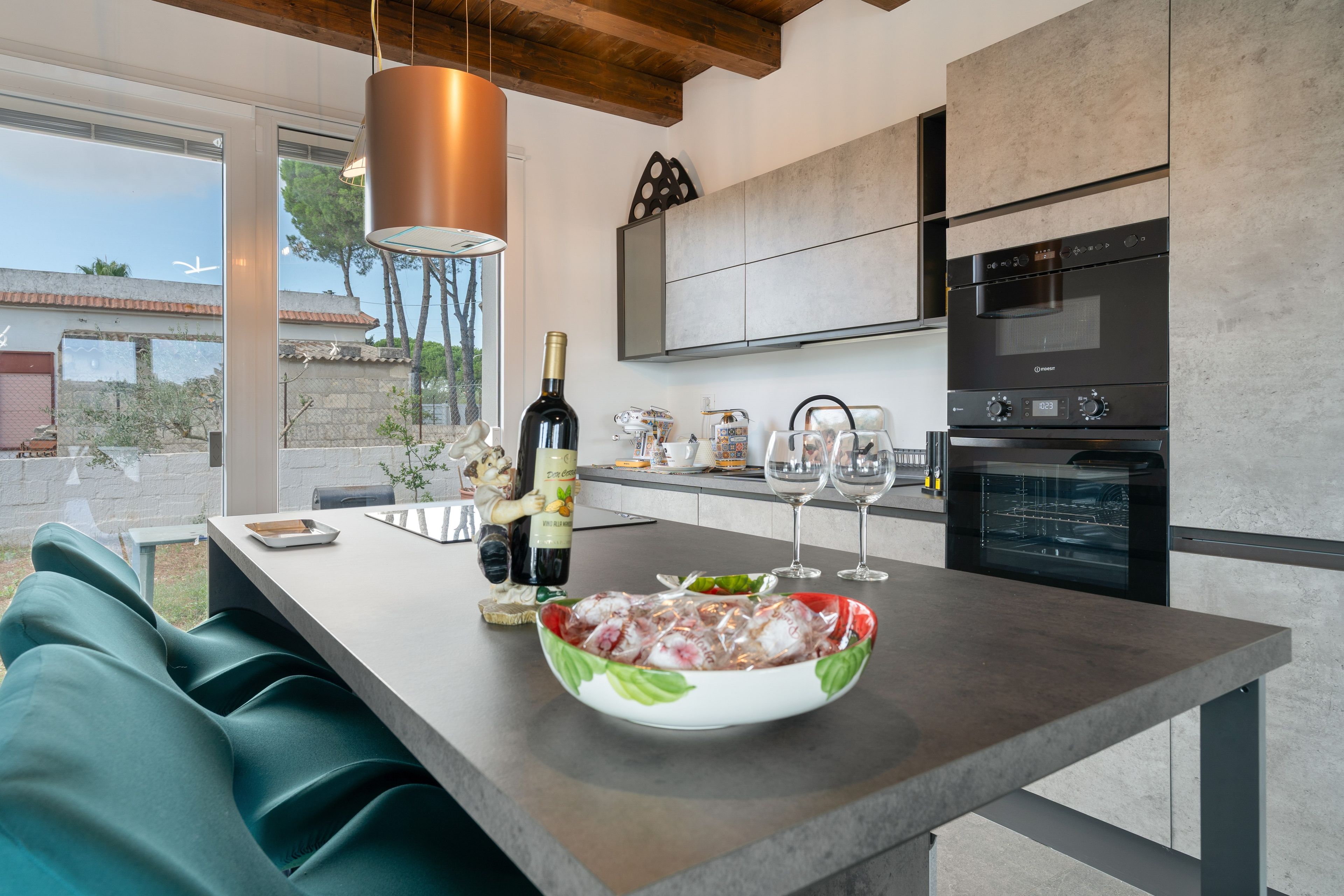 Une cuisine moderne dotée d’un grand îlot central, d’une bouteille de vin et d’un saladier rempli de fruits.