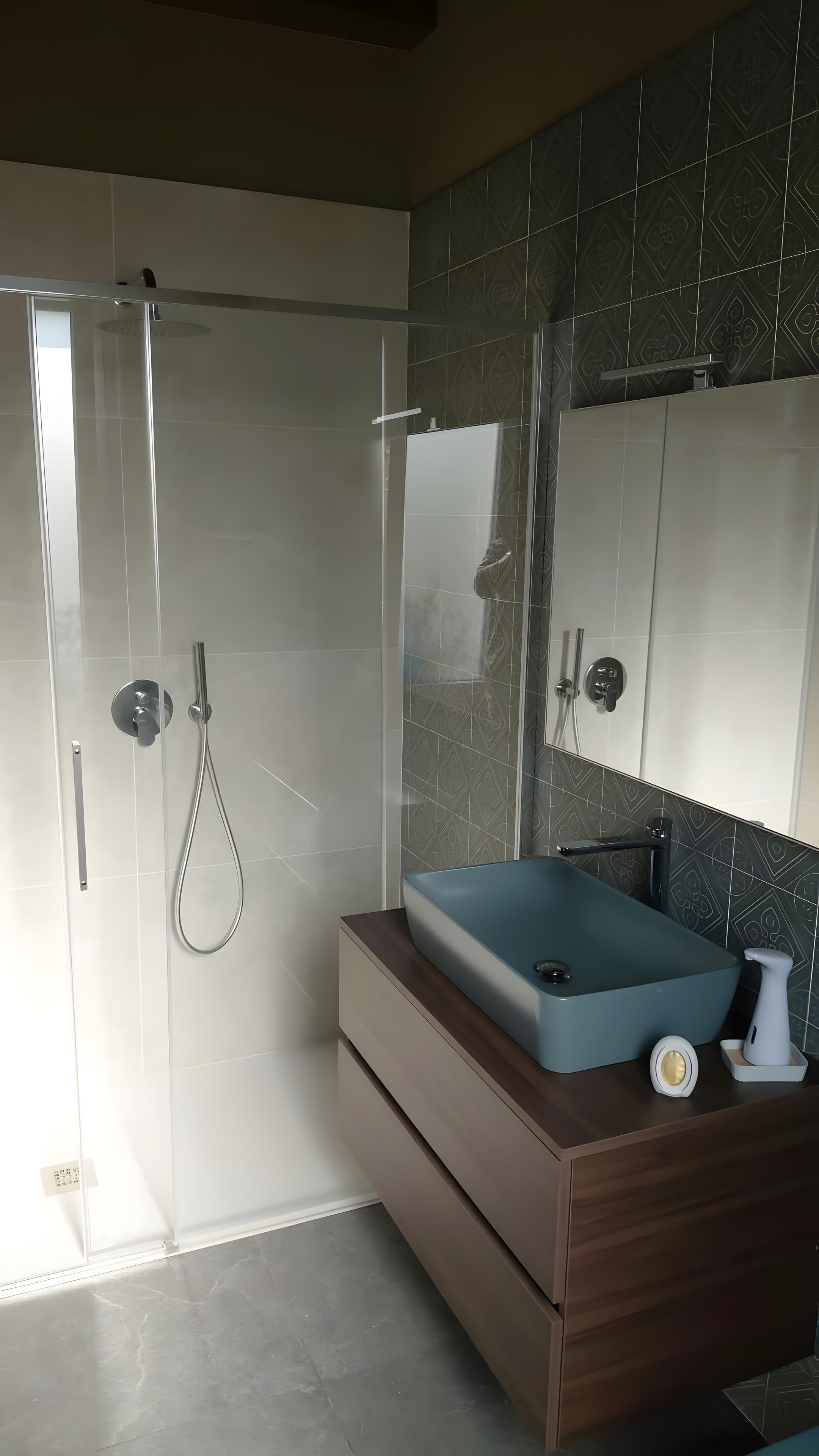 Casa de banho com cabine de duche em vidro, toucador com lavatório e espelho.