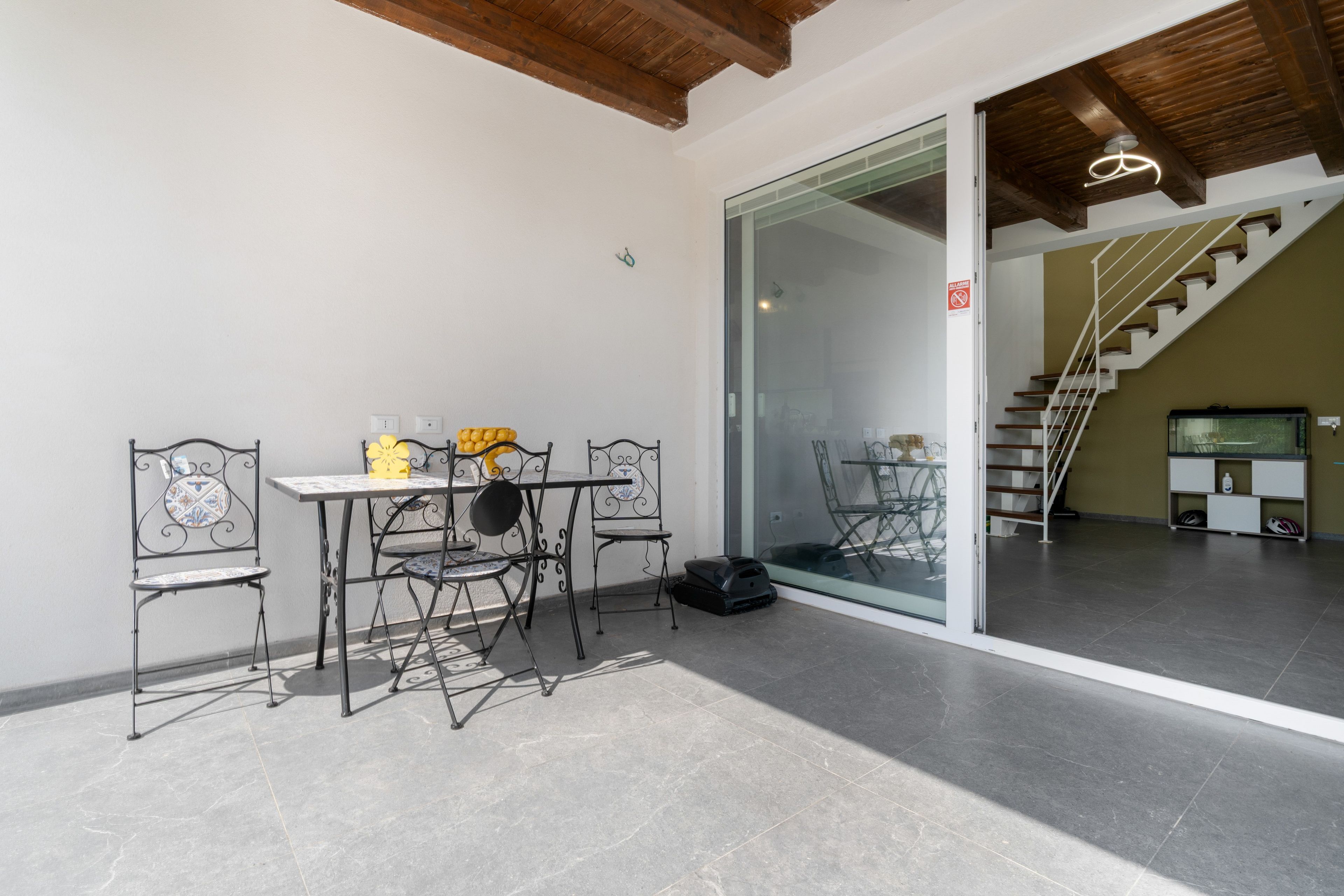 A room with a table and chairs, a sliding glass door, and a staircase leading to an upper level.