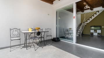 A room with a table and chairs, a sliding glass door, and a staircase leading to an upper level.