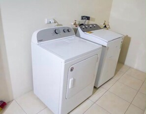 Een wasserette met twee witte wasmachines en een droger.