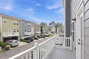 A residential street with townhouses, a clear sky, and a wooden deck.