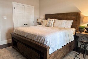 Un dormitorio con una cama de madera, una mesita de noche, una lámpara y un armario empotrado.