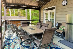 Un patio techado al aire libre con una mesa y sillas, un refrigerador y un reloj en la pared.