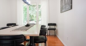 Ein Konferenzraum mit einem langen Tisch, schwarzen Stühlen und Blick auf Grün durch die Fenster.
