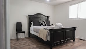 Une chambre à coucher avec un lit, une chaise et une fenêtre.