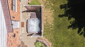 Eine Dachterrasse mit Whirlpool, Sitzgelegenheiten und einem kleinen Garten.