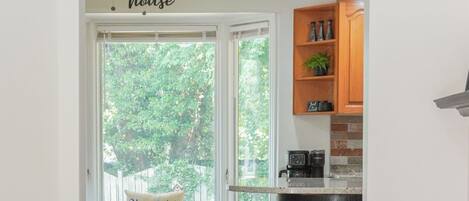 A kitchen with a window seat, wooden flooring, and a ceiling fan.