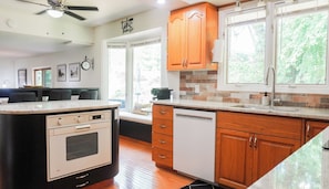 A kitchen with wooden cabinets, a built-in oven, and a dishwasher. - The Summer House - Lake Access - Hot Tub & Kayaks (Lambton Shores)