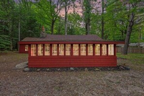 Eine rote Holzhütte mit vielen Fenstern, umgeben von Bäumen.