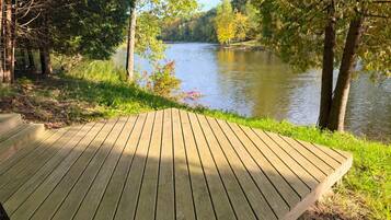 Una terraza de madera con vista a un río tranquilo flanqueado por árboles.