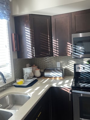 A modern kitchen with dark wooden cabinets, a stainless steel sink, a coffee maker, and a toaster. - 🌿 JAVA HOUSE | Private Stay, No Sharing • Free Coffee, Breakfast & Parking (Edmonton)