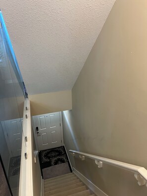 A staircase with a handrail, a carpeted landing, and a door with a handle. - 🌿 JAVA HOUSE | Private Stay, No Sharing • Free Coffee, Breakfast & Parking (Edmonton)