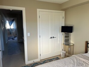 A hotel room with a closed wardrobe, a television mounted on the wall, and a bed with a patterned bedspread. - 🌿 JAVA HOUSE | Private Stay, No Sharing • Free Coffee, Breakfast & Parking (Edmonton)