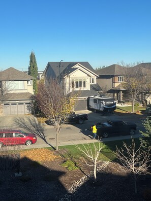 A residential street with houses, a parked truck, and a red car. - 🌿 JAVA HOUSE | Private Stay, No Sharing • Free Coffee, Breakfast & Parking (Edmonton)