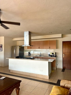 A modern kitchen with a central island, built-in cabinets, and a microwave. - Excellent location (Puerto Vallarta)