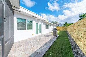 Una casa moderna con patio, barbecue e recinzione in legno.