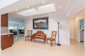 A spacious living area with a wooden bench, a framed picture on the wall, and a floor lamp. - Relaxed Retreat with Porch Dining and Yard (Lighthouse Point)
