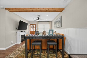 Ein Essbereich mit Holzbalkendecke, Deckenventilator, Fernseher und Kamin.