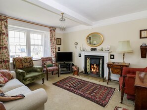 A traditional living room with a fireplace, television, and seating area. - Ivy Cottage (Buxton)