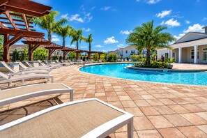 A pool area with lounge chairs, a pergola, and palm trees. - 15mins Disney~Themed Suites~Resort Pool~Game Room (Kissimmee)