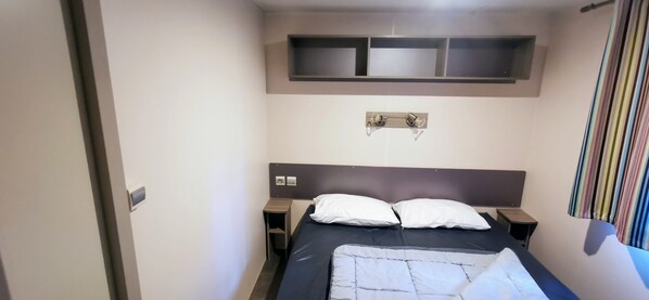 Ein Schlafzimmer mit einem Bett, Nachttischen, einer Kopfteil, einem Regal über dem Bett und einem Vorhang.