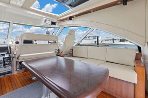 Interior de barco con tragaluces, asientos acolchados y cubierta de madera.