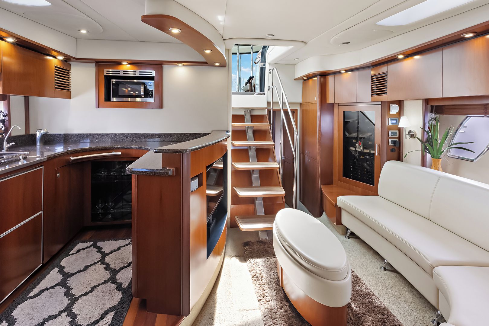 A compact kitchen with a microwave, a sink, and a built-in oven. There is a staircase leading to an upper deck.
