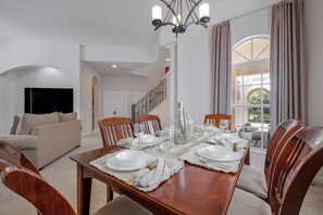A dining area with a wooden table set for six, surrounded by wooden chairs. - Luxury 6-Bed Villa with Pool & Spa near Disney (Davenport)