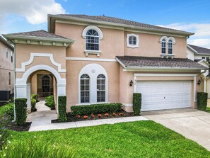 A two-story house with a garage, a covered entryway, and a well-maintained lawn. - Luxury 6-Bed Villa with Pool & Spa near Disney (Davenport)