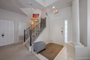 A spacious hallway with a staircase, white doors, and a beige carpet. - Luxury 6-Bed Villa with Pool & Spa near Disney (Davenport)