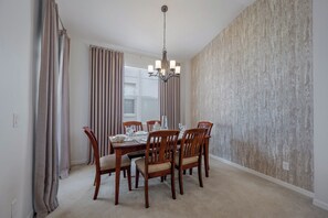Een eetkamer met een houten tafel en stoelen, een kroonluchter en een structuurwand.