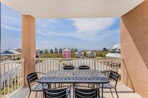 Un balcón con mesa y sillas, con vistas a una zona costera con casas de colores.