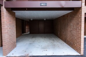 A parking garage with brick walls and a concrete floor, featuring a door with a metal gate and a sign above it. - Park Avenue 311 - Park City Vacations (Park City)
