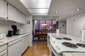 A modern kitchen with white cabinetry, a built-in microwave, a coffee maker, and a stove. - Park Avenue 311 - Park City Vacations (Park City)