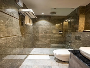 A modern bathroom with a marble floor, a white toilet, a black countertop sink, and a glass shower enclosure. - Premium King Bed Room (Agra)