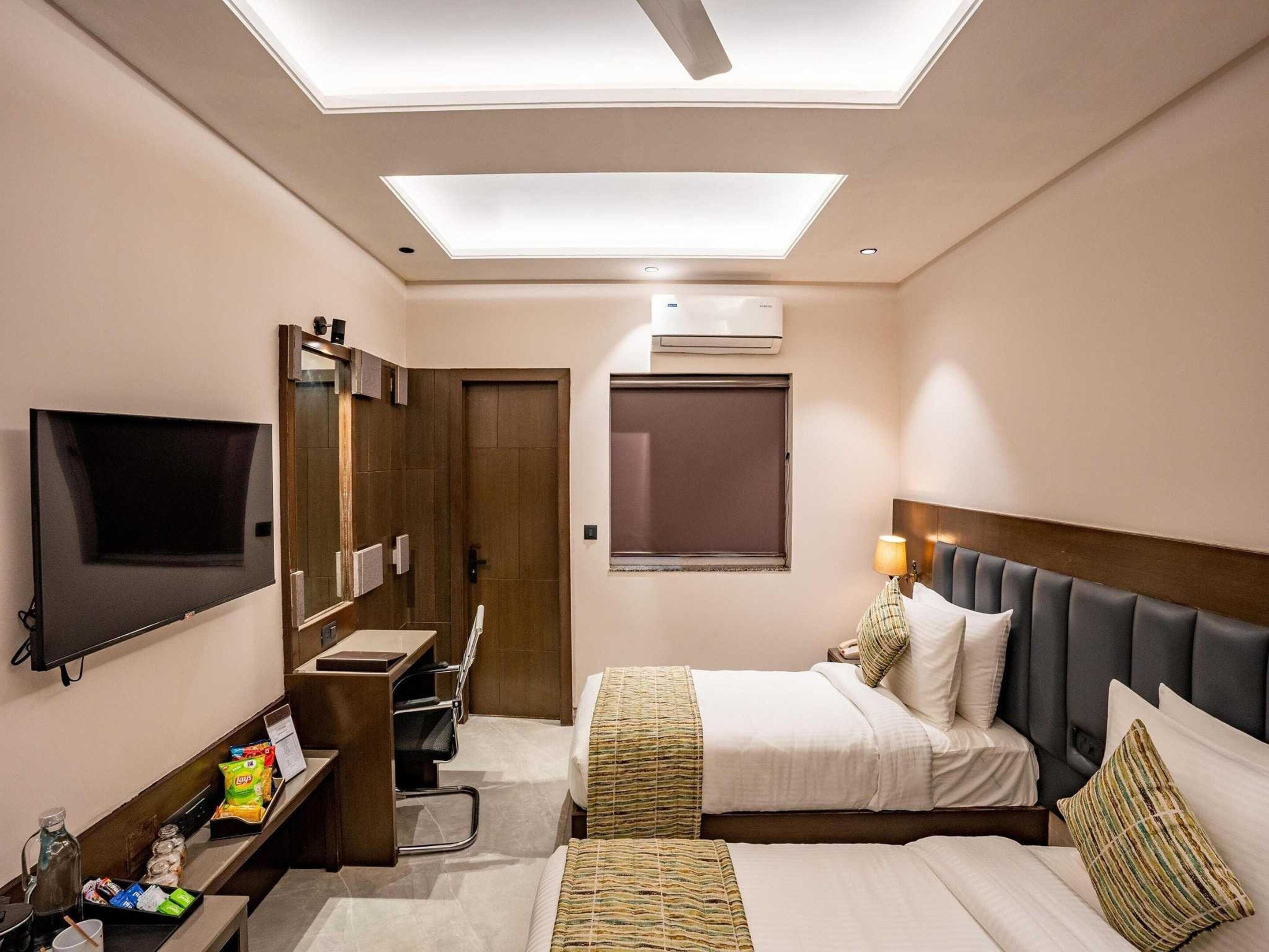 A hotel room with a bed, desk, TV, and a ceiling light.