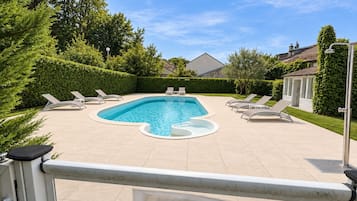 Una piscina con lettini, immersa nel verde sotto un cielo sereno.