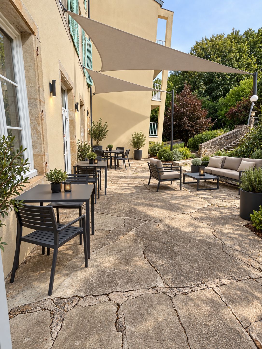 Un'area patio esterna con pavimento in pietra, tavoli, sedie e un divano.