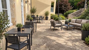Un'area patio esterna con pavimento in pietra, tavoli, sedie e un divano.