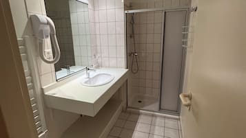 Un bagno con lavandino bianco, specchio e doccia.
