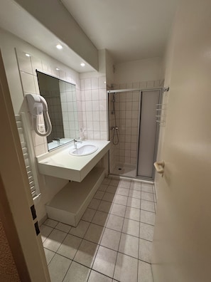 A bathroom with a white sink, mirror, and shower. - Hôtel d'orfeuil (Bourbonne-les-Bains)