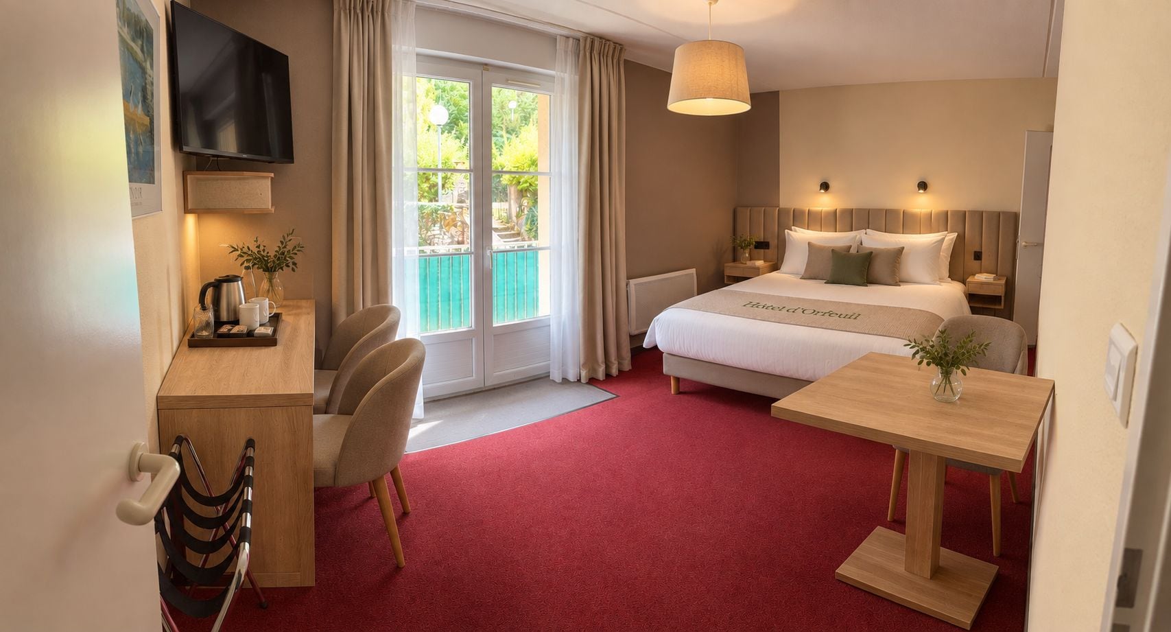 A hotel room with a bed, a desk, a chair, a table, a TV, and a window with curtains.