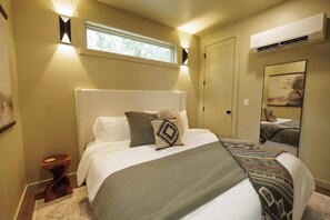 A bedroom with a large bed, a window, an air conditioning unit, and a mirror. - The Ranger - Luxury Treehouse (Pikeville)