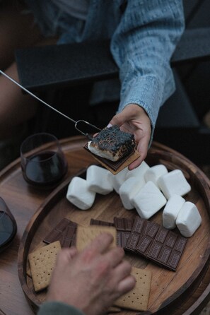 A wooden tray with marshmallows, chocolate bars, and a piece of chocolate cake. - The Ranger - Luxury Treehouse (Pikeville)