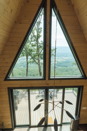 Ein Zimmer mit großen Fenstern und Blick auf eine bewaldete Landschaft.