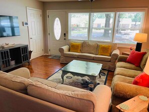 A living room with a sofa, a coffee table, a TV, and a window with blinds. - Robin's Nest 3 bed/1 bath/15 mins to Ft Benning (Columbus)