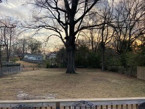 A backyard with a large tree, a wooden fence, and houses in the background. - Robin's Nest 3 bed/1 bath/15 mins to Ft Benning (Columbus)