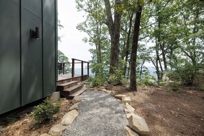 A pathway leading to a wooden deck with a view of the water. - The Collins - Luxury Treehouse (Pikeville)